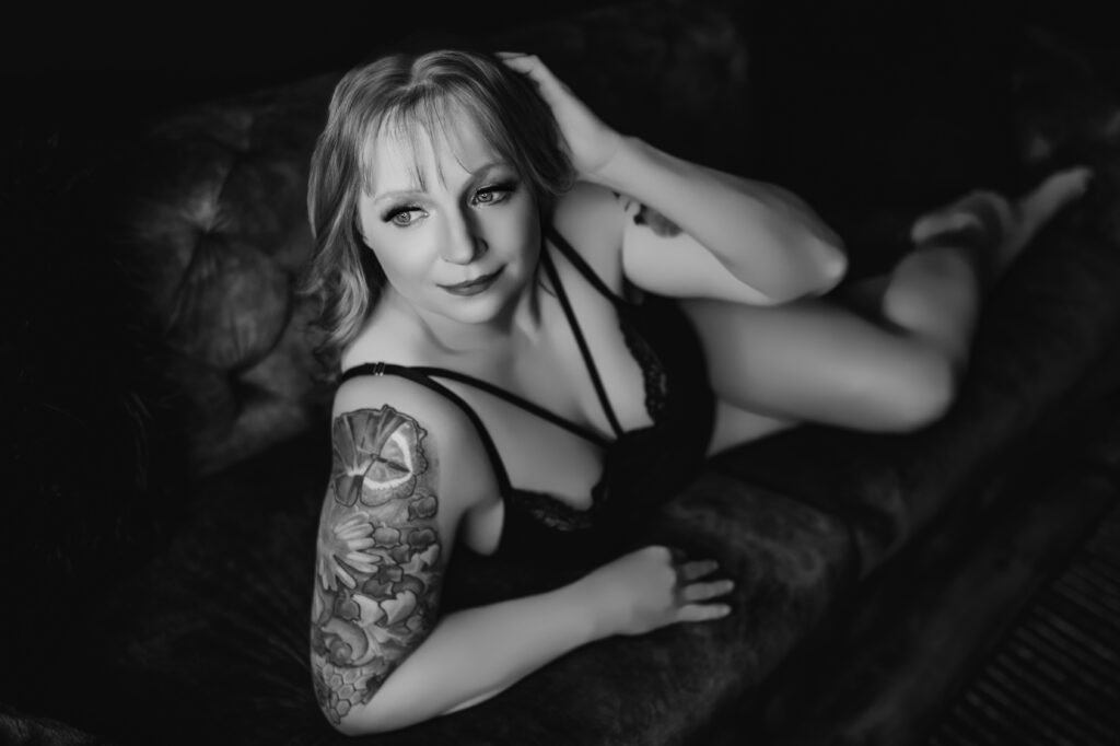 Confident woman posing on a vintage couch during her boudoir photoshoot session at Moonlight and Lace Boudoir